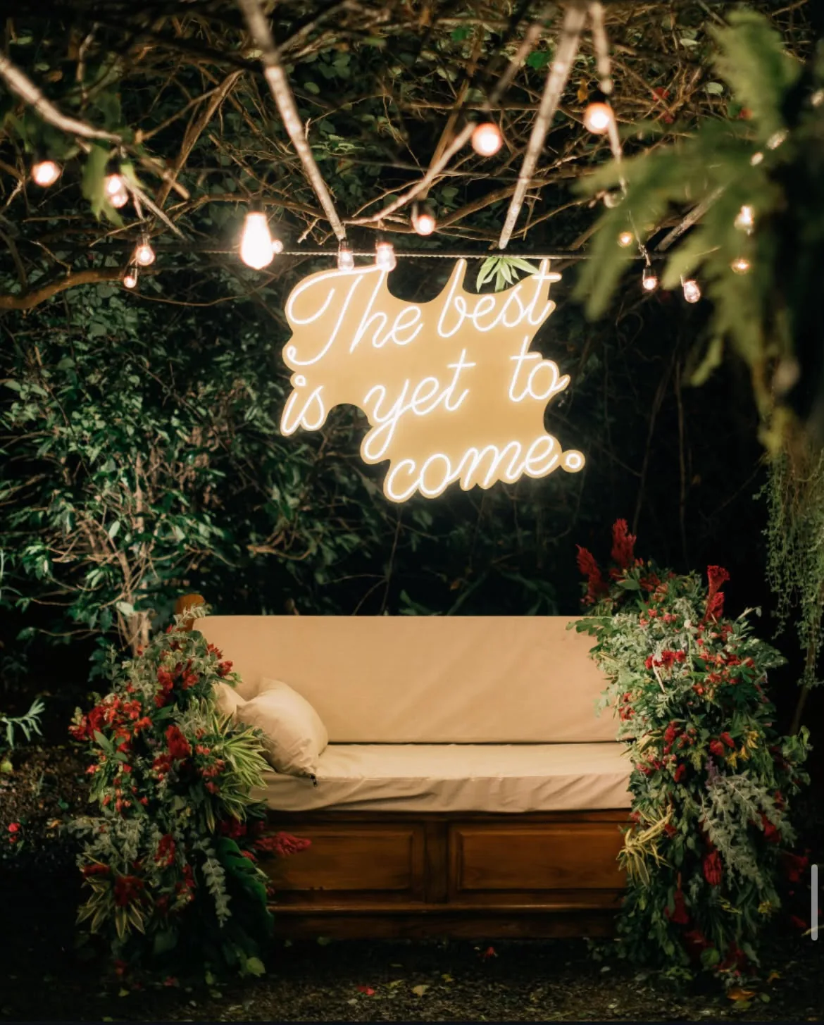 Letreiro em neon sobre sofá decorado com flores
